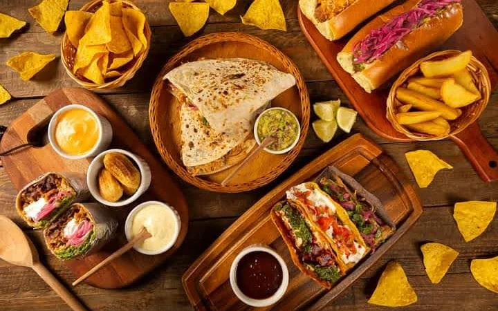 Mesa de comida mexicana com nachos, guacamole, quesadilla, tacos e burritos do Buffet Paladare