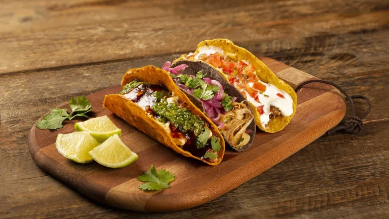 Tacos com frango desfiado, carne e molhos na tábua