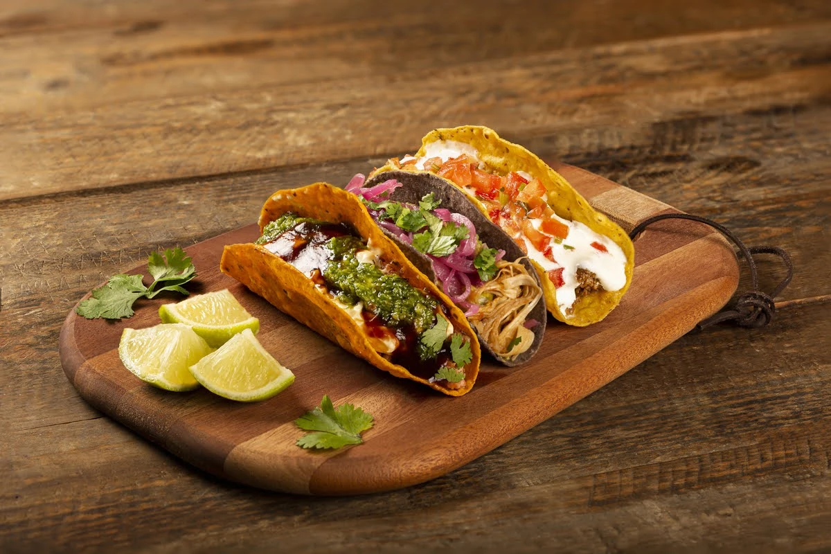 Tacos com frango desfiado, carne e molhos na tábua